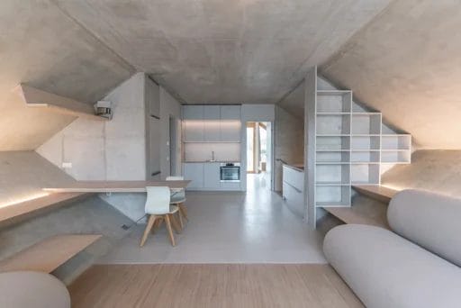 Wohn-Essbereich im Inneren des Wabenhauses. Die schiefen Ebenen sind als Sitzbänke gestaltet, die Wände sind "roh" im Loft-Stil.