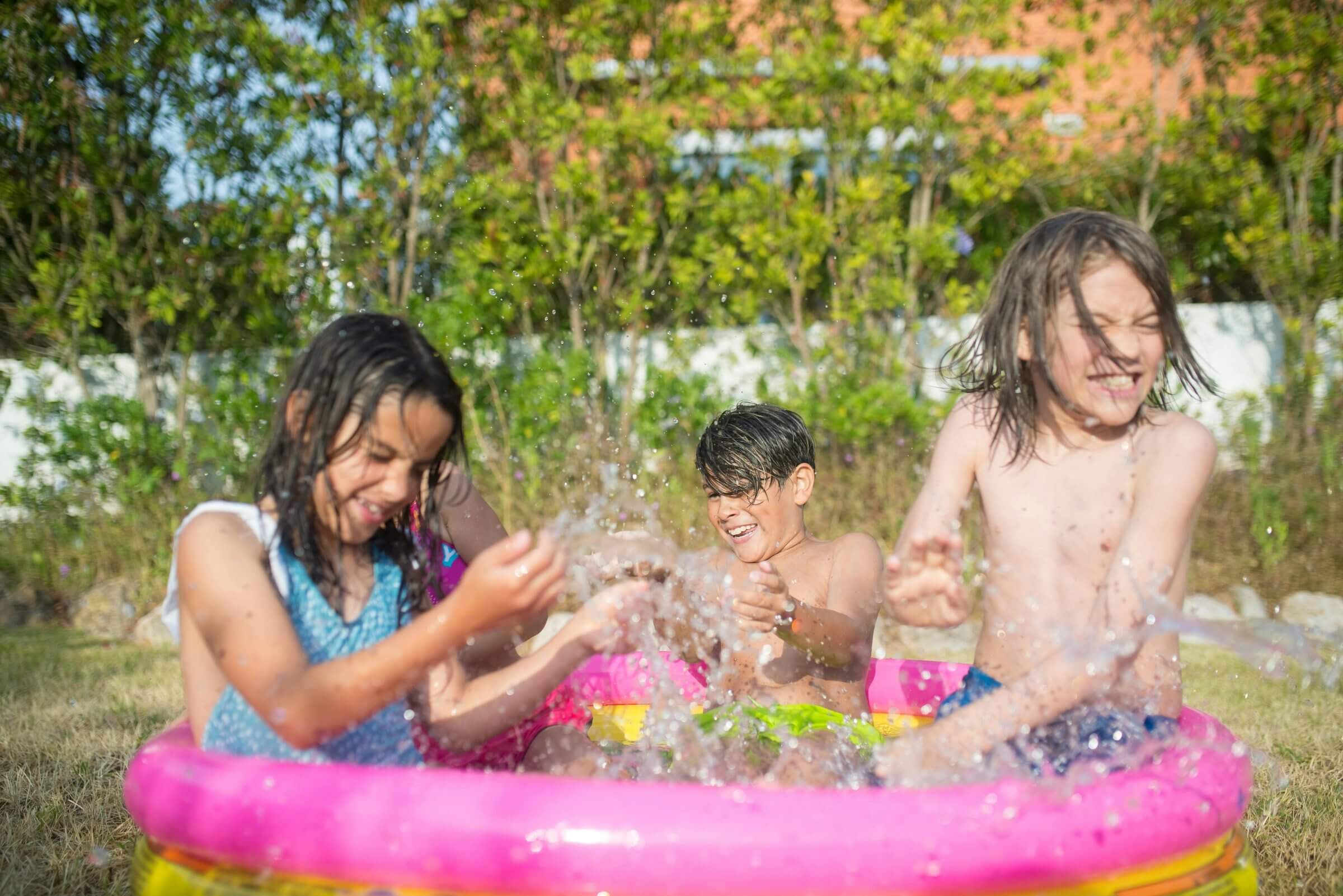Kinder planschen im aufblasbaren Plastikpool im Garten. 