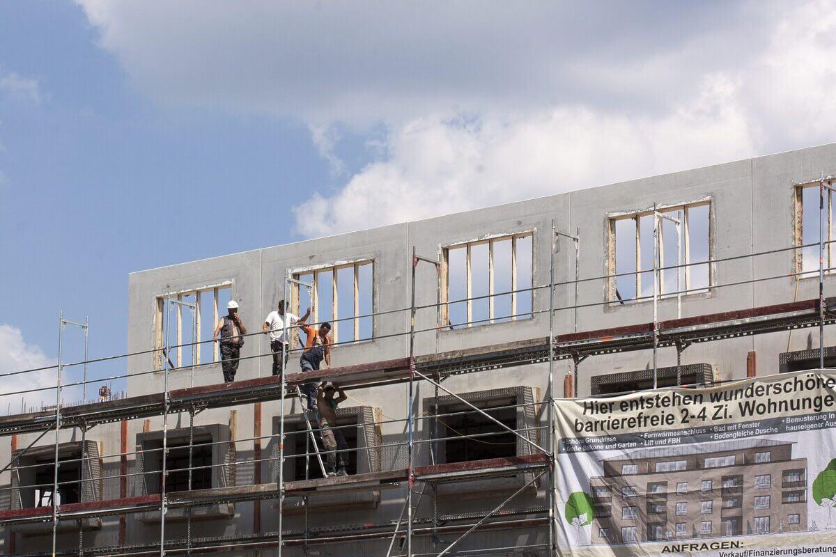Bauarbeiter auf einem Baugerüst. Es entsteht ein Neubau-Mehrfamilienhaus. 